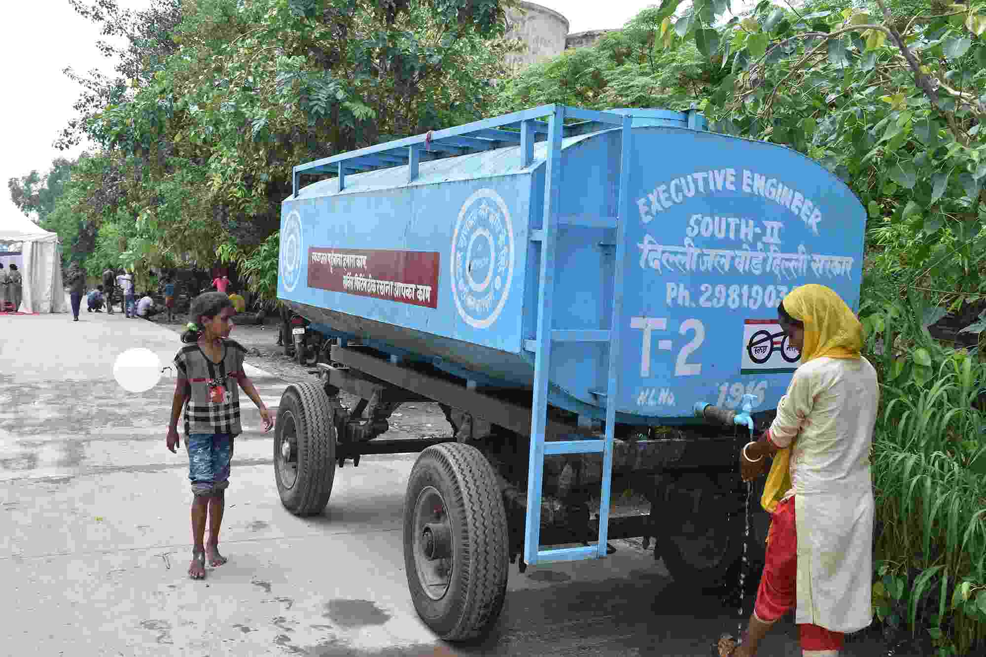 A woman draws drinking water from a water tanker provided by Delhi Jal Board (the city's water supply agency) at a makeshift relief camp during the Yamuna flood in 2019, India