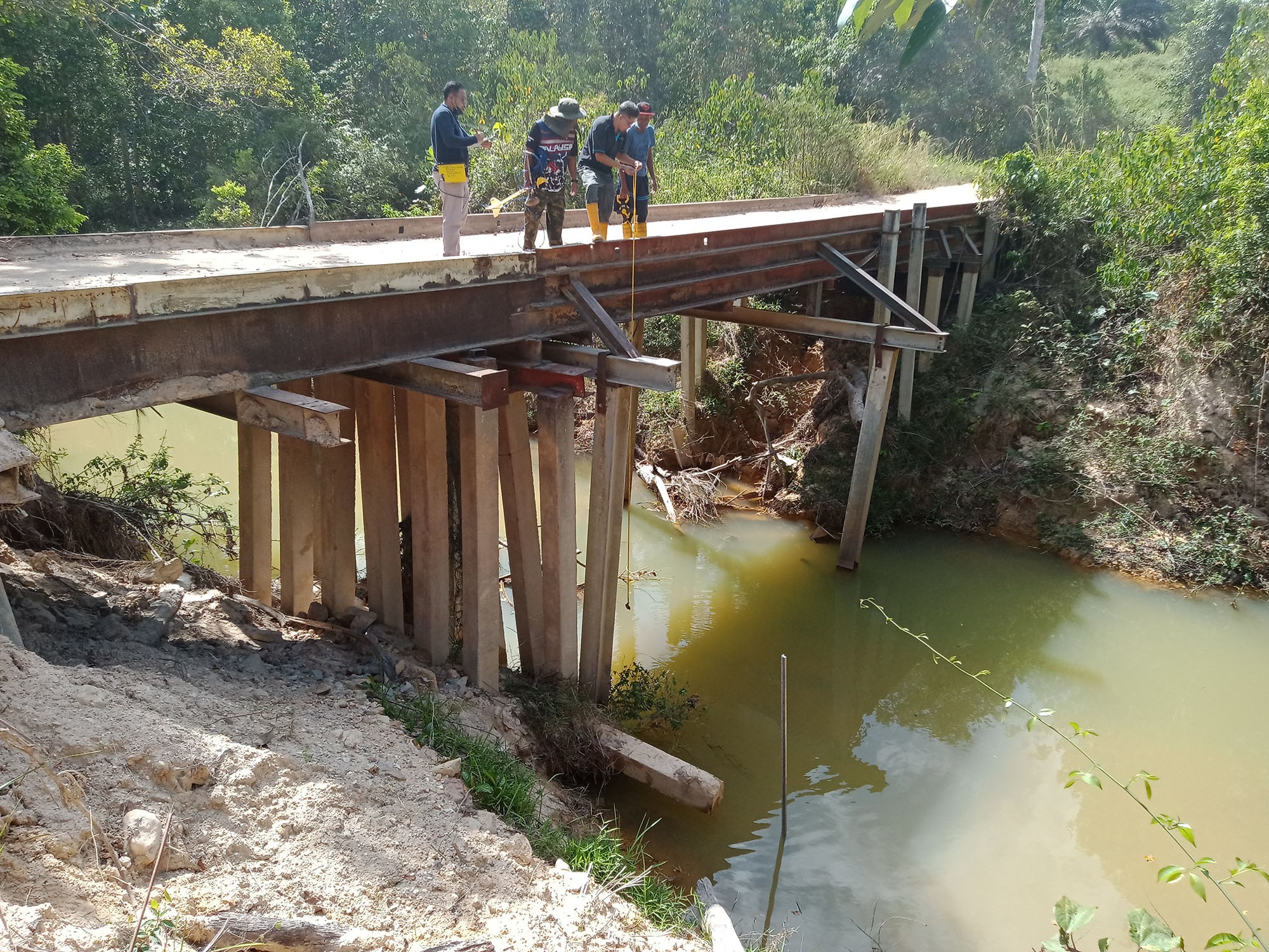 UTM colleagues lower equipment from a steel bridge into the river water below as part of Flowrate channel determination work